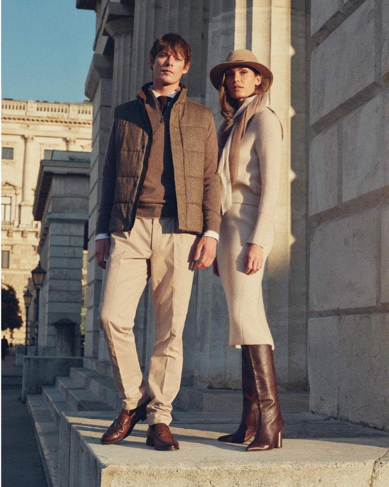 Two people standing on stone steps in front of a classical building wearing N.Peal cashmere