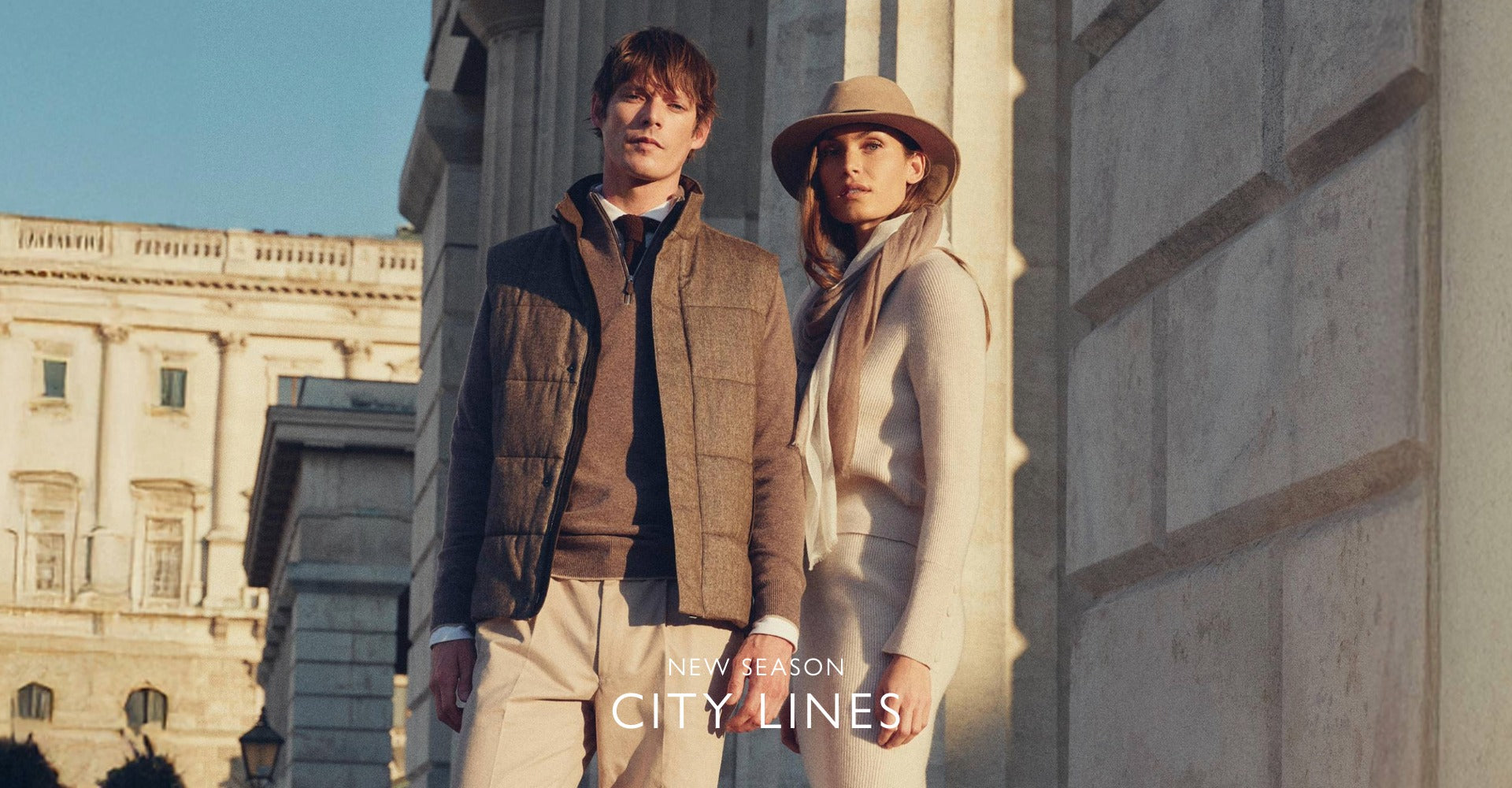 Two people wearing N.Peal cashmere standing in front of a building with 'New Season City Lines' text