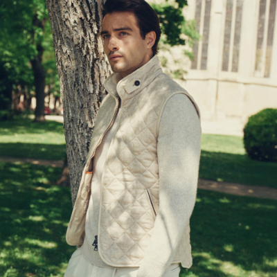 Man wearing a gilet standing next to a tree in a park