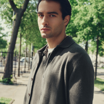 Man wearing N.Peal cashmere standing outdoors with trees in the background