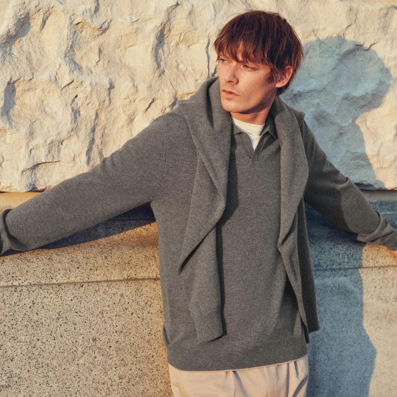 A male model wearing N.Peal cashmere leaning against a stone building
